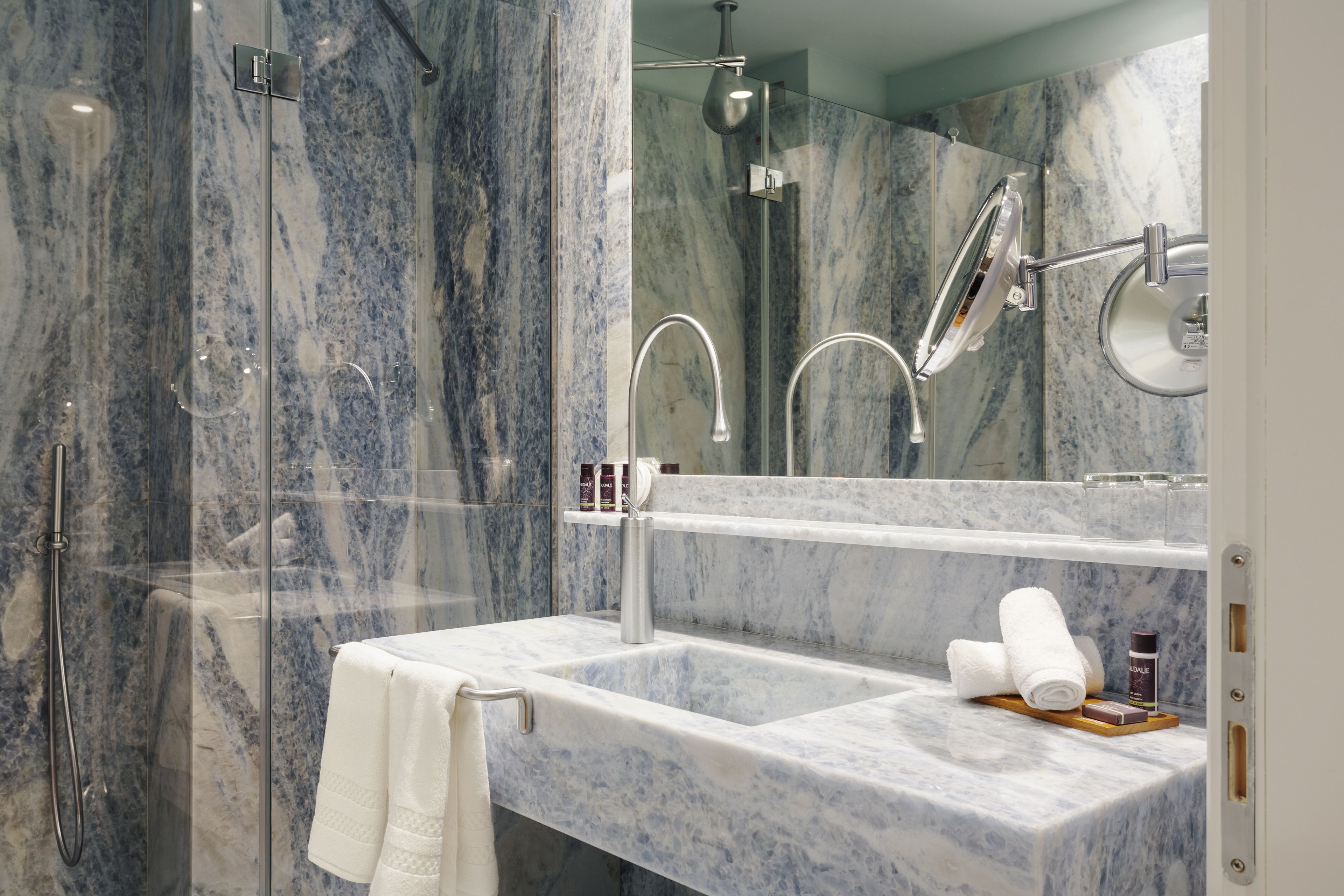 A bathroom with a marble sink, a glass-enclosed shower, and a mirror.