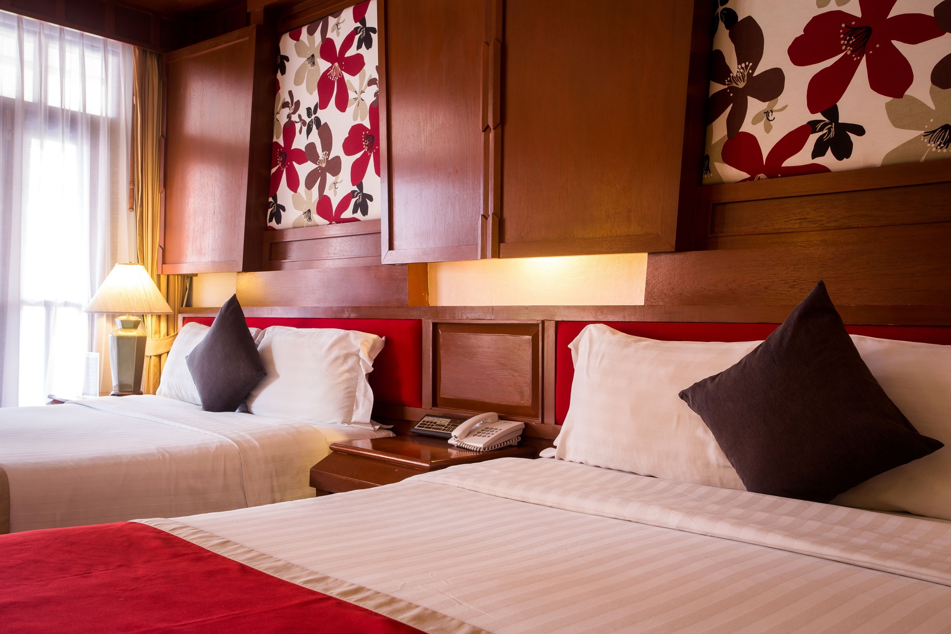 Una habitación de hotel con dos camas, una mesita de noche con teléfono y una ventana con cortinas.