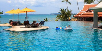 Una piscina al aire libre, sombrillas, sillones reclinables de piscina