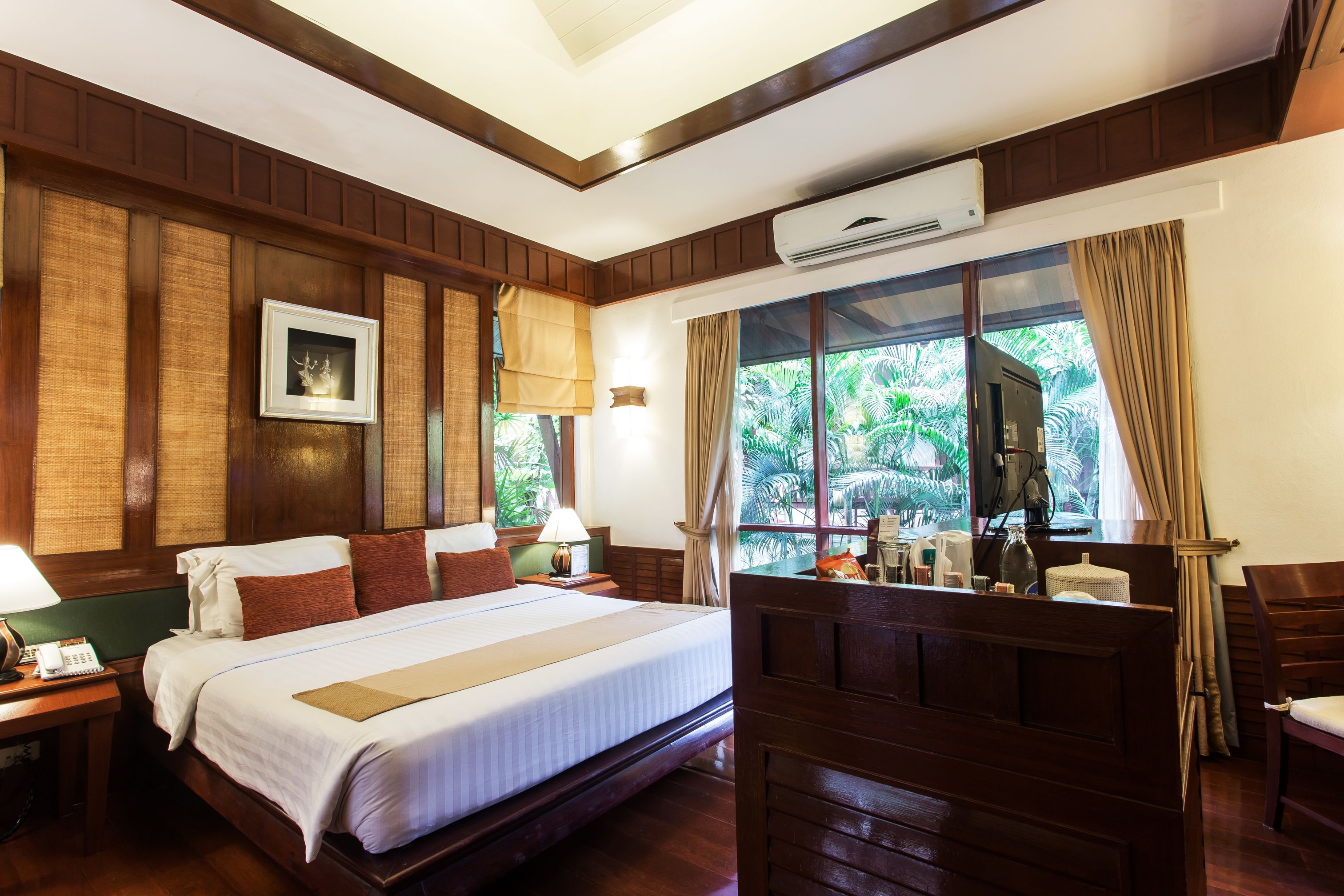Quarto de hotel com uma cama grande, painéis de madeira, um quadro na parede e uma janela com cortinas.