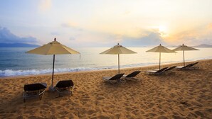 Una playa con cuatro sombrillas y sillas de playa.