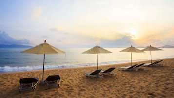 På stranden, hvit sand, solsenger og parasoller