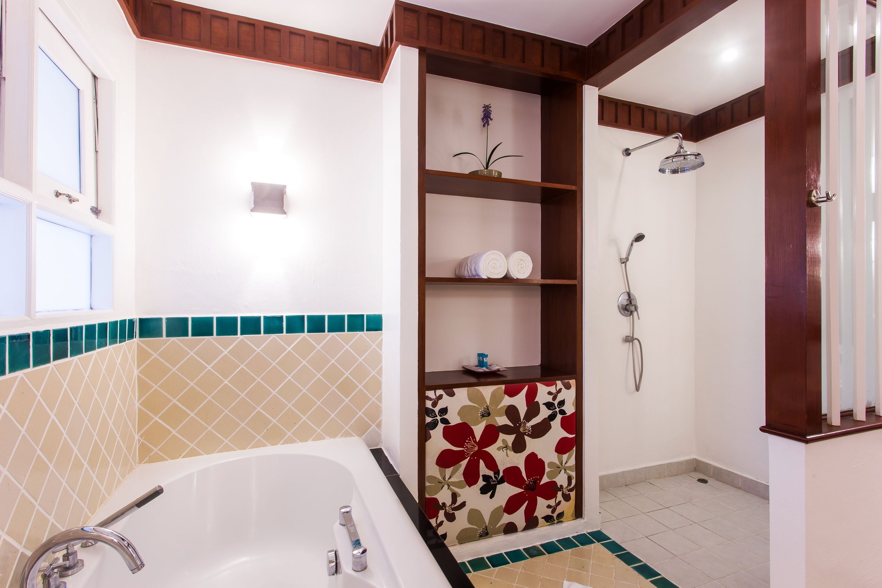 A bathroom with a bathtub, shower, and shelves with toiletries.
