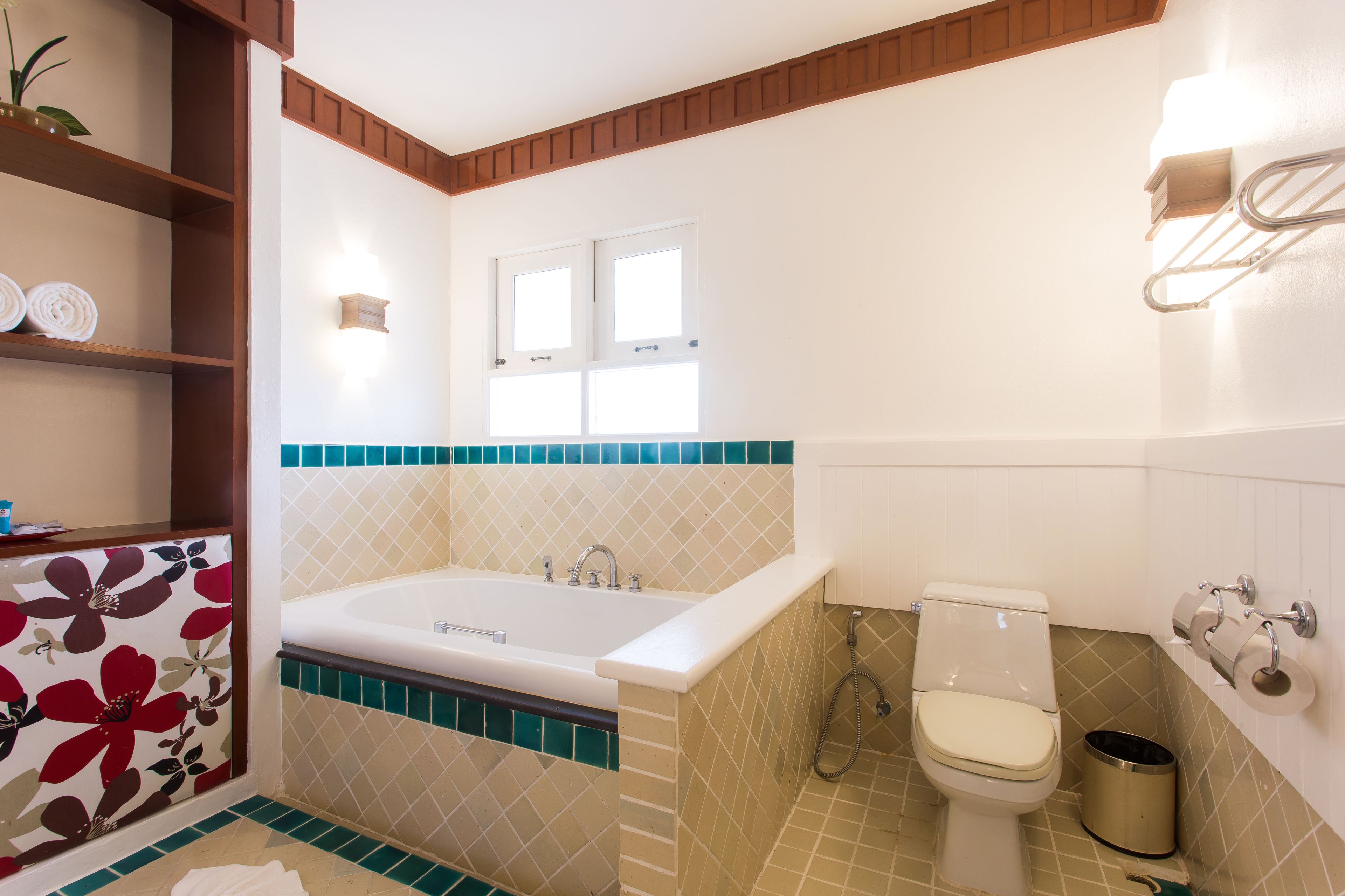 A bathroom with a bathtub, toilet, and a window.