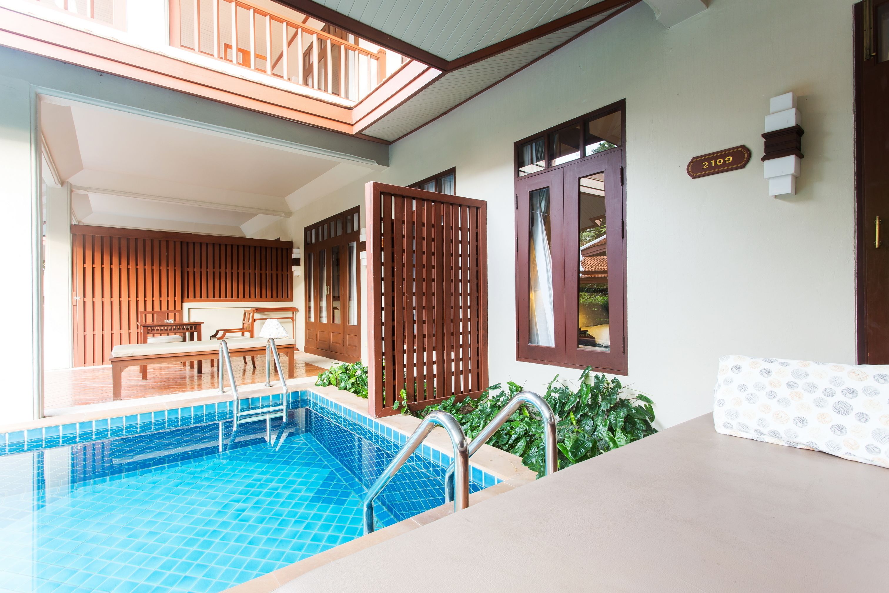 A pool area with a wooden deck, a lounge chair, and a poolside table.