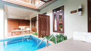 A pool area with a wooden deck, a lounge chair, and a poolside table.