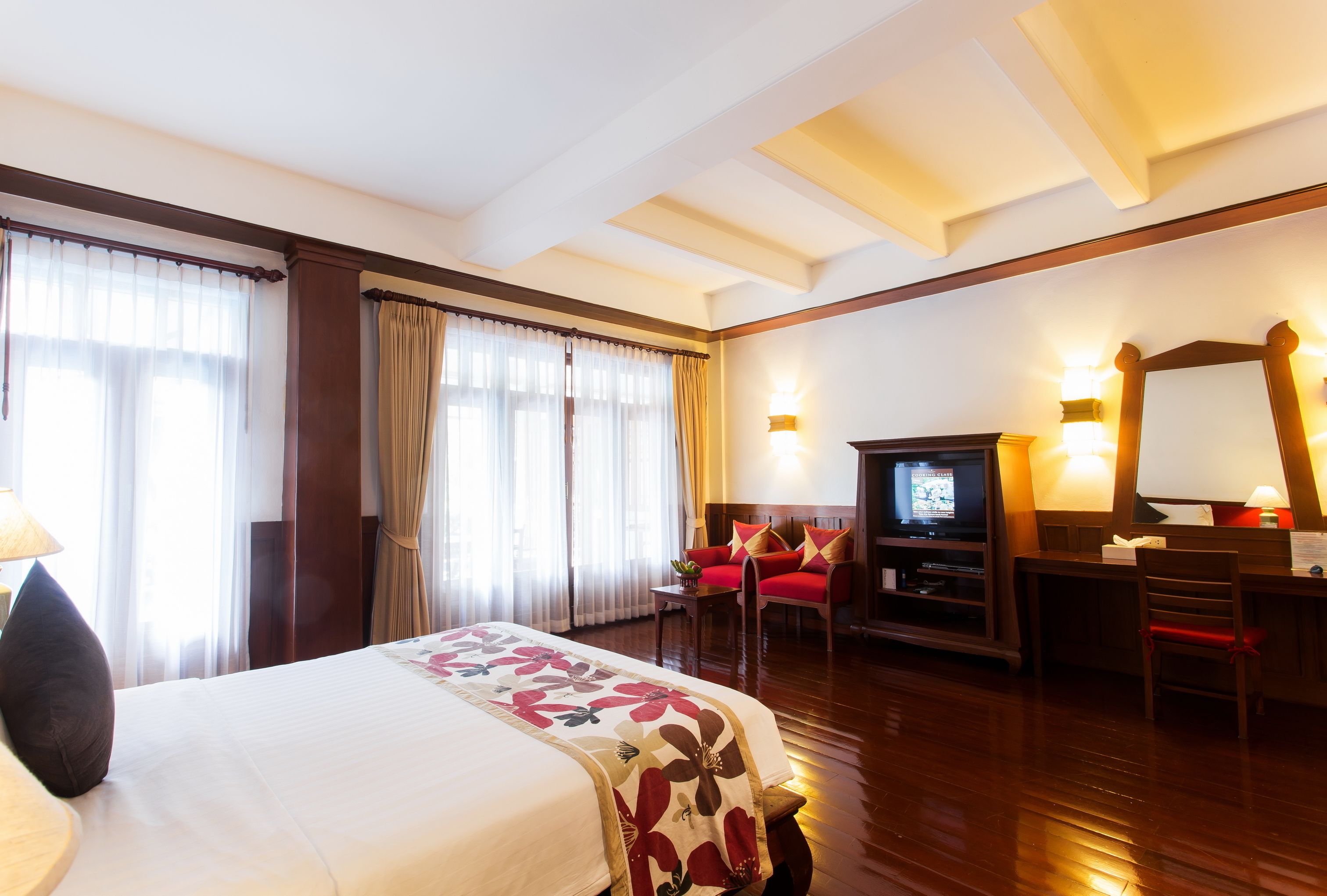 A hotel room with a large bed, a desk with a computer, a TV, and a chair.