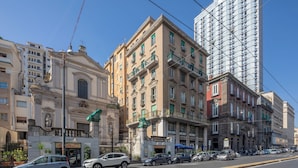 Vista de la calle con edificios históricos, un rascacielos moderno y coches estacionados.