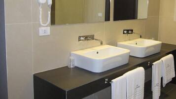 A modern bathroom with two sinks, a hairdryer, and a mirror.