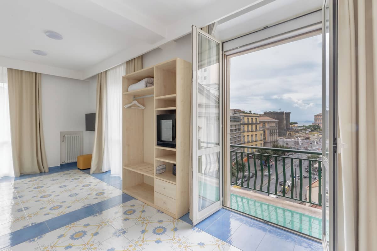 A spacious balcony with a city view, a wooden wardrobe, and a radiator.