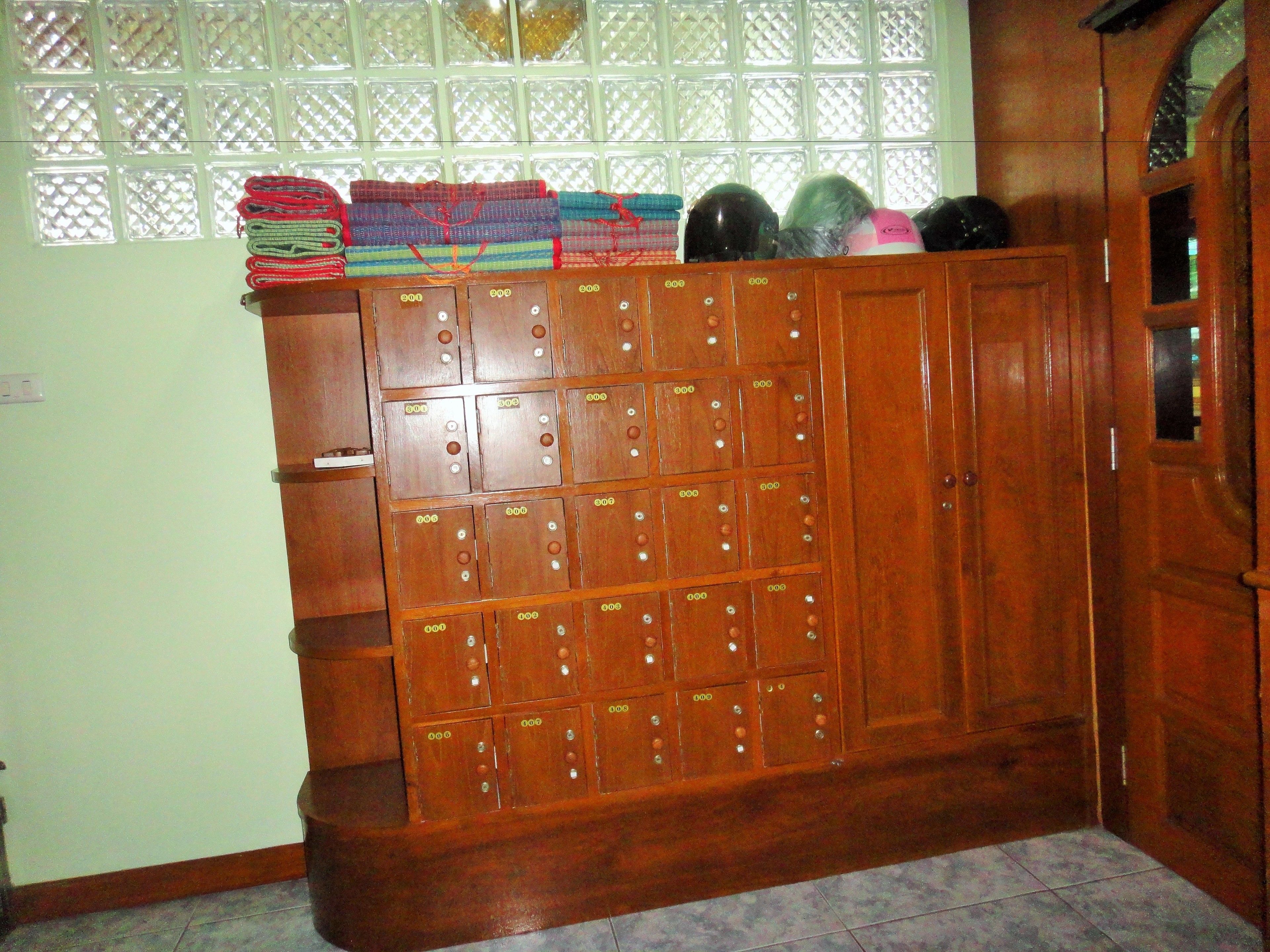 A wooden locker room with multiple lockers, a tiled floor, and a window with a lattice design.