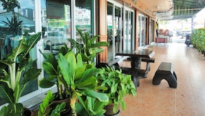 A restaurant with outdoor seating, large windows, and potted plants. - Thepparat Lodge Krabi (Krabi)