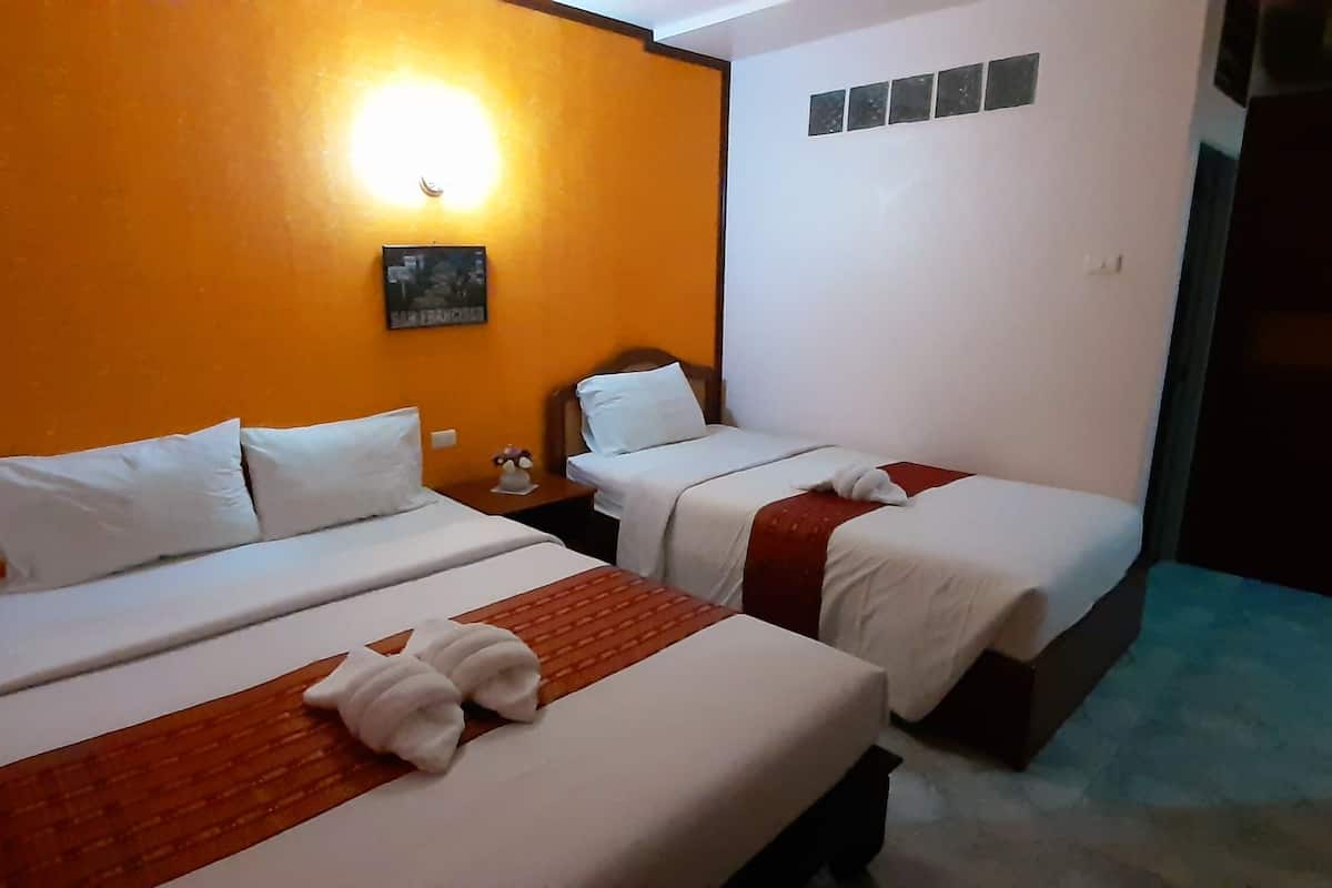Una habitación de hotel con dos camas, una mesita de noche, una lámpara fijada a la pared y una puerta.