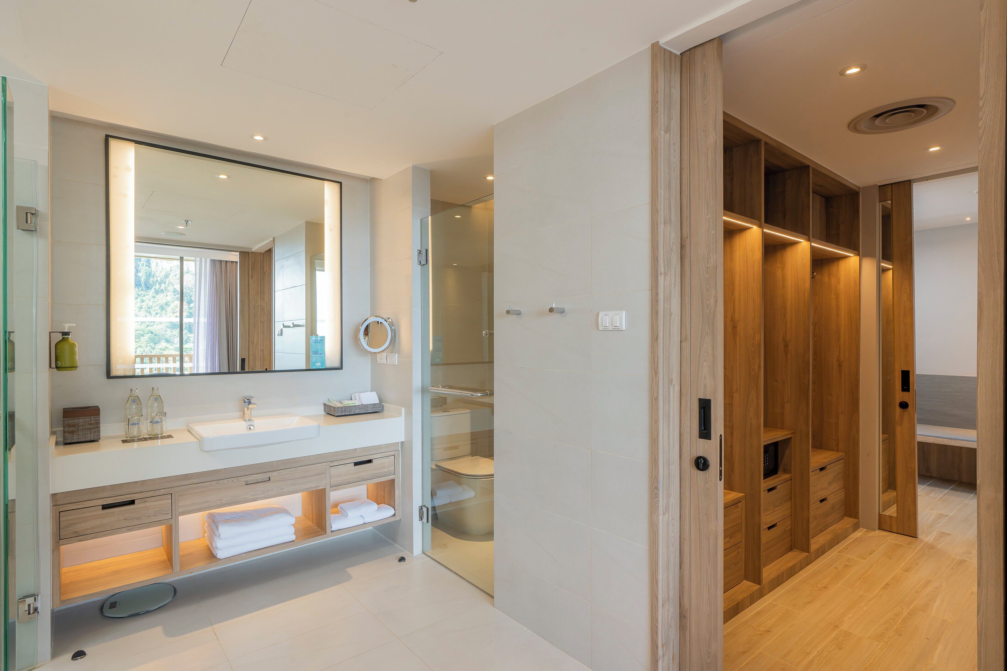 A modern bathroom with a large mirror, dual sinks, and a walk-in shower.