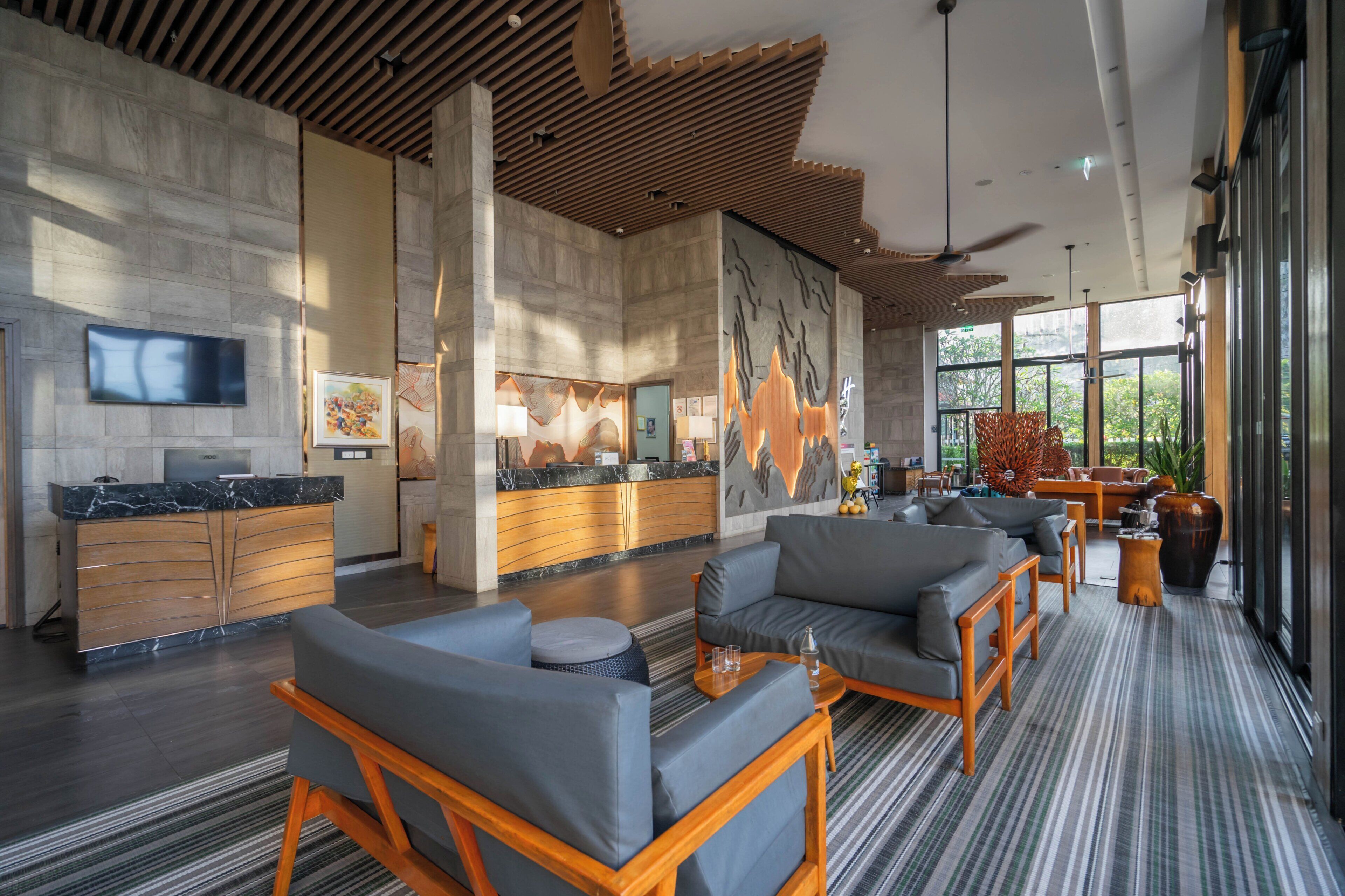 A modern lobby with a reception desk, seating area, and large windows.