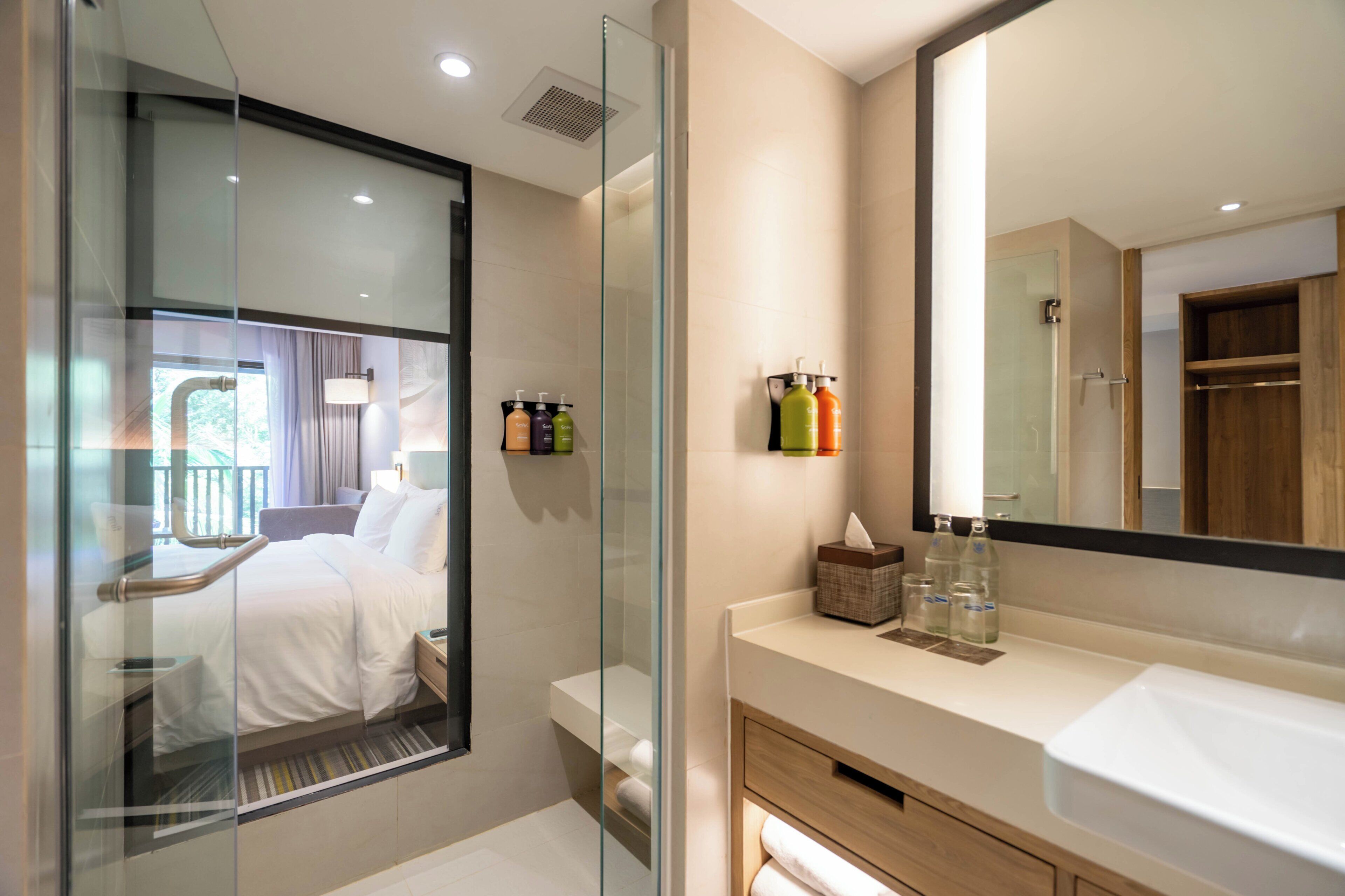 Un baño moderno con cabina de ducha de vidrio, un espejo grande y un tocador con artículos de aseo.