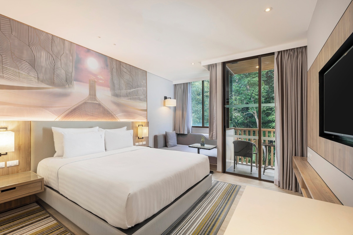 Une chambre d’hôtel moderne dotée d’un grand lit, d’une télévision à écran plat, d’un balcon offrant une vue sur l’extérieur et d’un tableau accroché au mur.