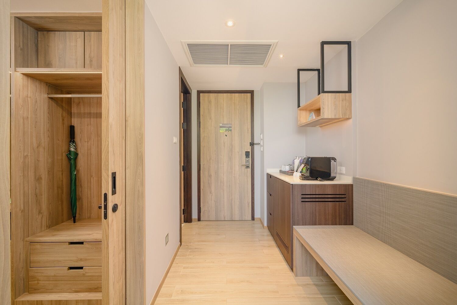 A hallway with wooden cabinets, a microwave, and a bench.