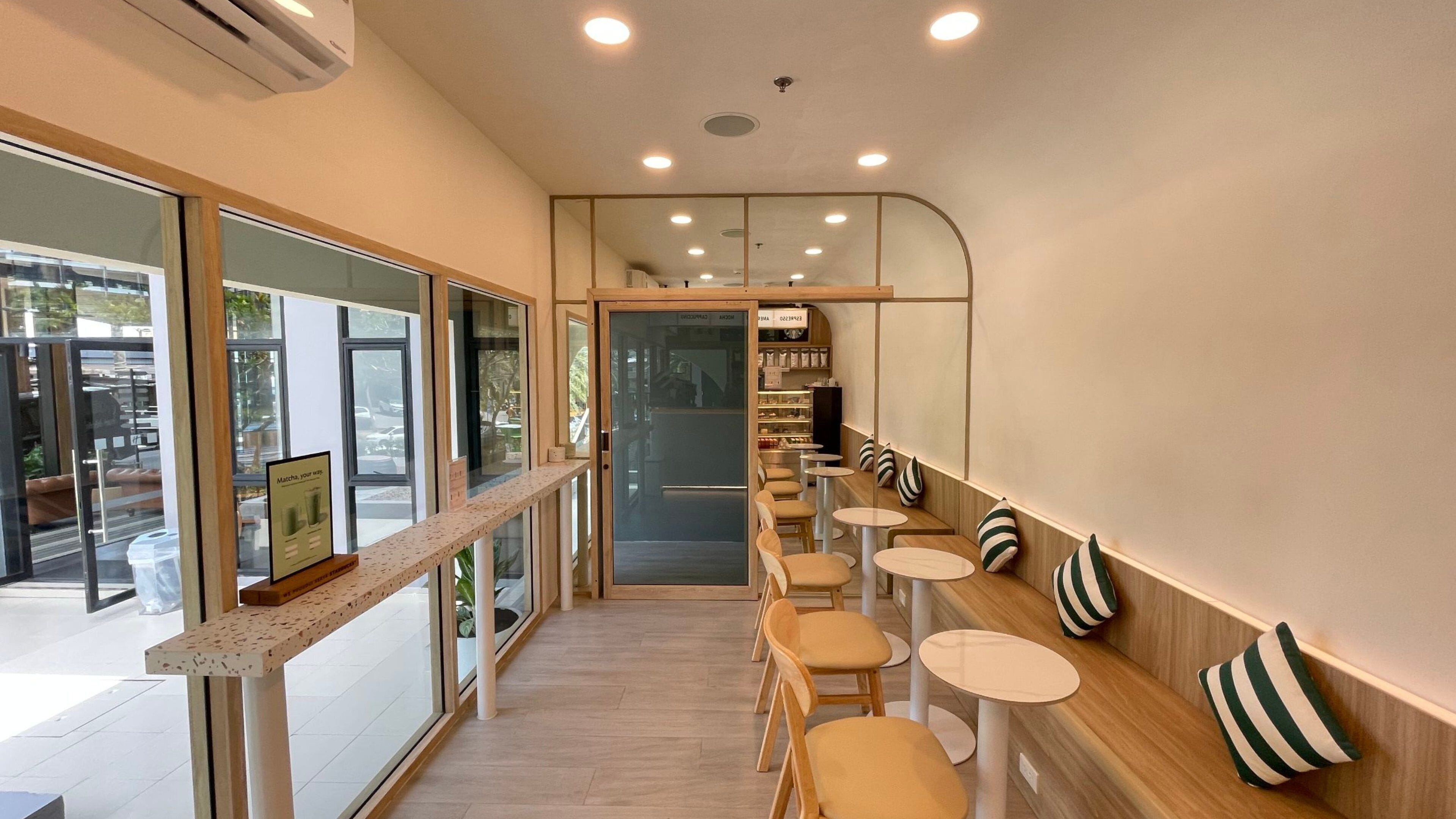 A modern cafe interior with a long counter, seating area, and a view through large windows.