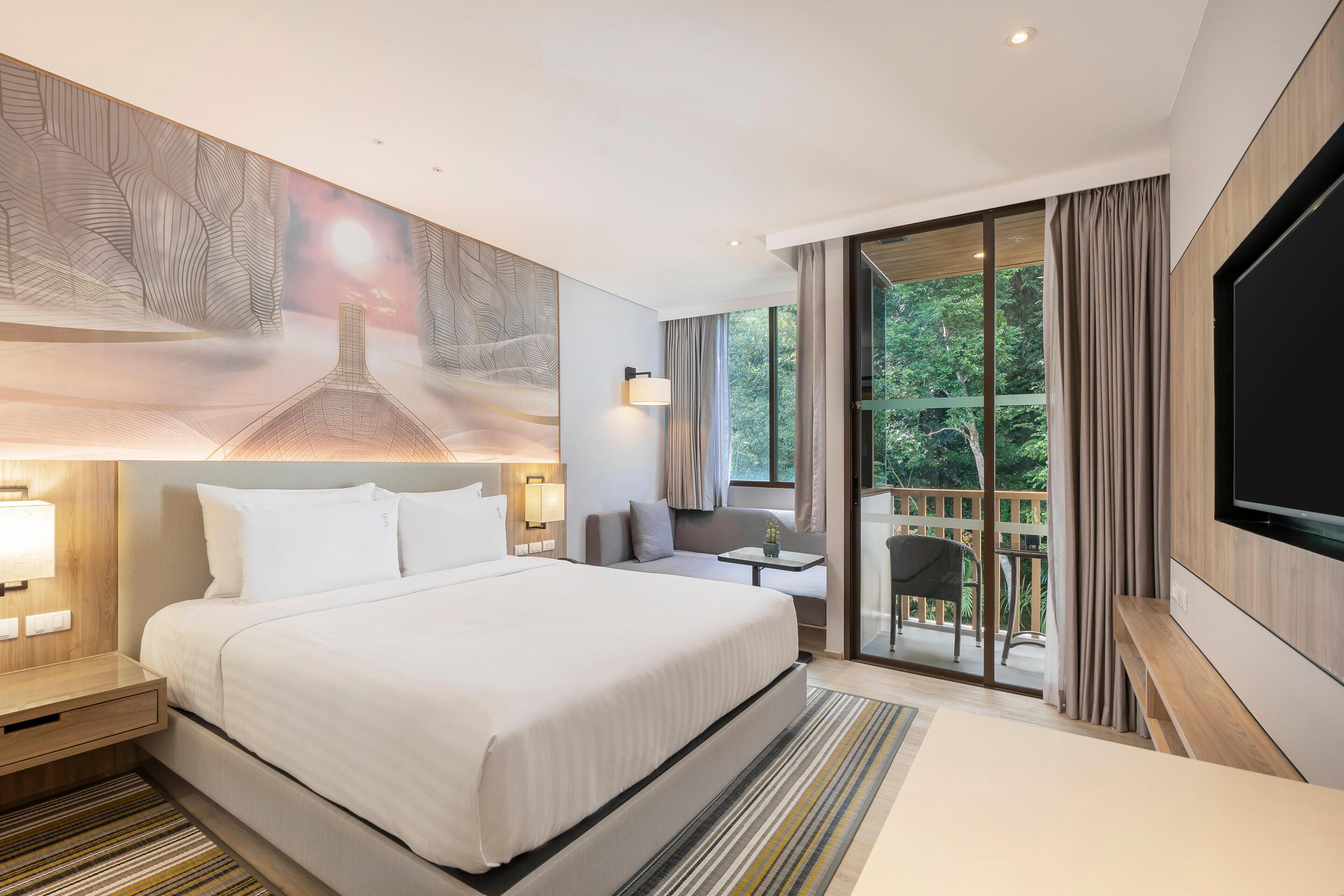Habitación de hotel con una cama grande, televisión, balcón con vistas a árboles y un cuadro en la pared.