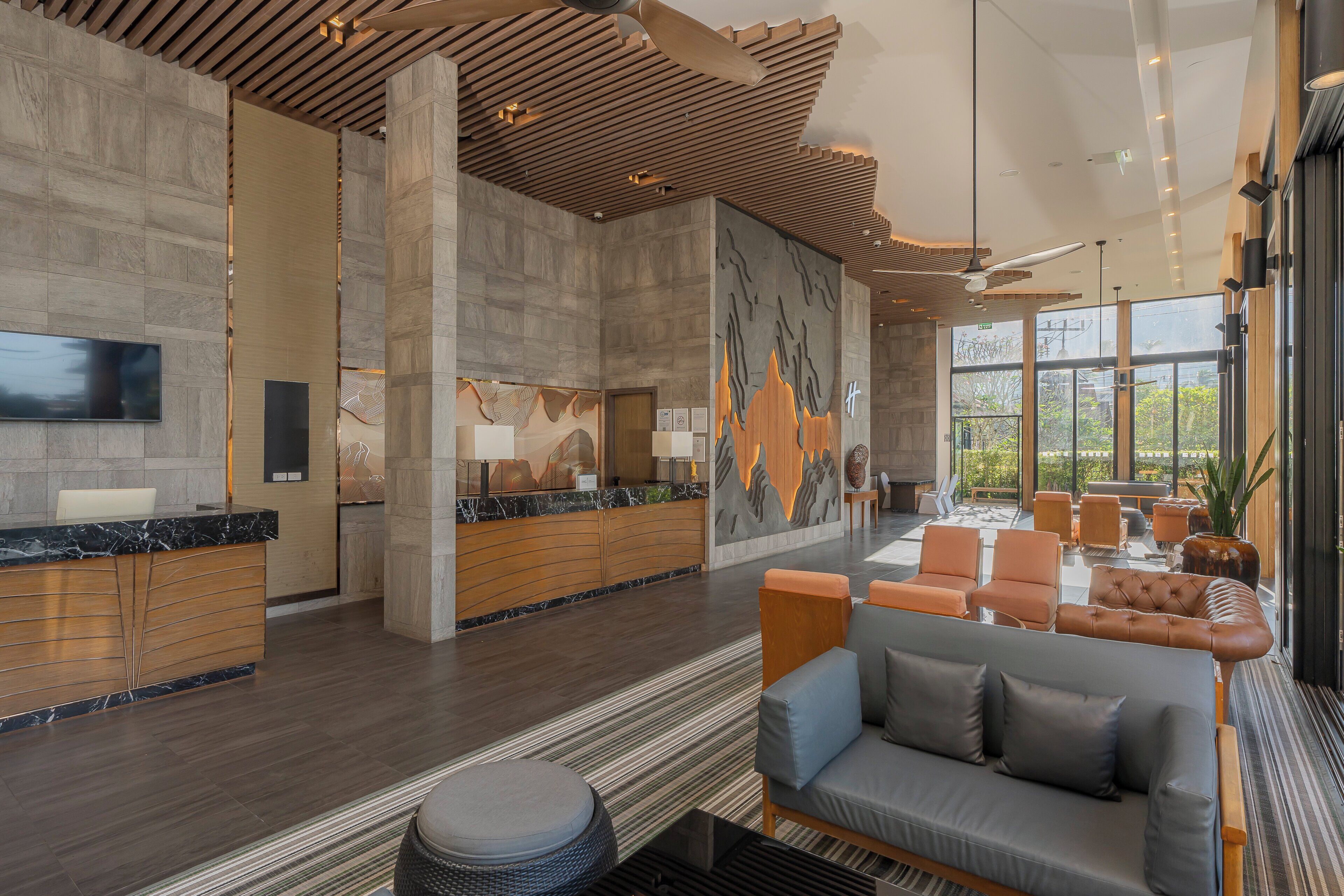 A modern lobby with a reception desk, seating area, and large windows.