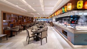 A modern restaurant with a long counter, multiple tables, and a decorative ceiling. - Sheraton Changsha Hotel (Changsha)