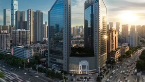 A high-rise building with a distinctive logo on the side, surrounded by other tall buildings in a cityscape. - Sheraton Changsha Hotel (Changsha)