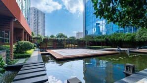 A modern building with a reflective glass facade, a rooftop garden, and a water feature with a wooden deck. - Sheraton Changsha Hotel (Changsha)