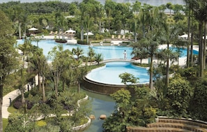 Un resort con múltiples piscinas rodeado de exuberante vegetación y palmeras.