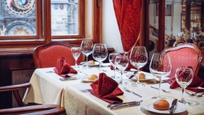 A dining table set with wine glasses, plates, and silverware, with a red napkin folded on the table. - Grand Hotel Praha (Prague)