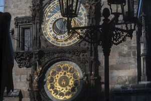 Um relógio grande e ornamentado com desenhos intrincados e mostrador dourado, fixado em um edifício de pedra.