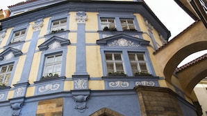 A corner building with blue and yellow facades, multiple windows, and decorative moldings. - Grand Hotel Praha (Prague)