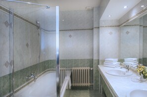 Un bagno con doccia vetro, lavandino bianco e specchio.