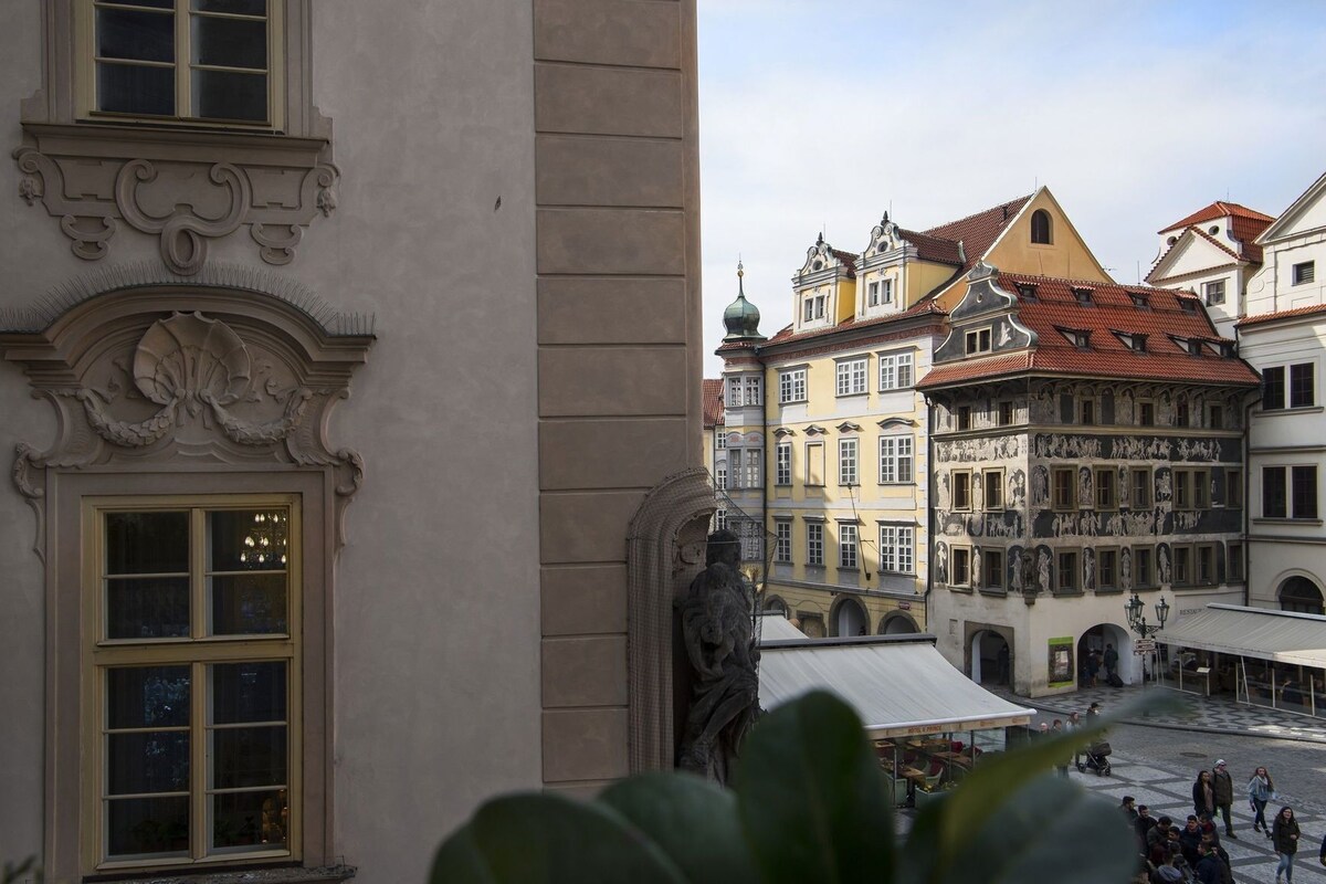 A building with ornate architectural details, a statue, and a courtyard with people.