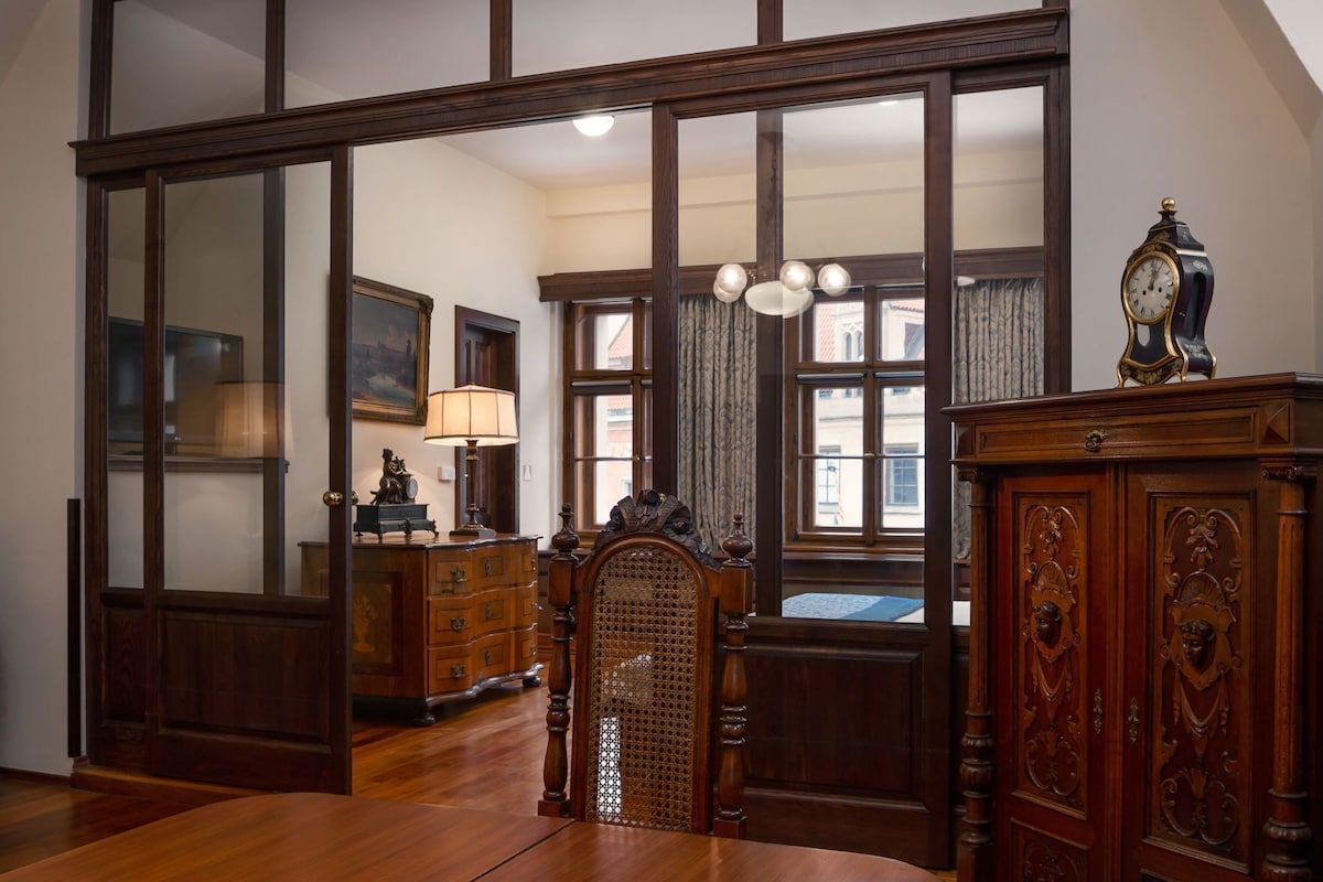 Una habitación con un espejo grande, muebles de madera, una araña y un reloj.