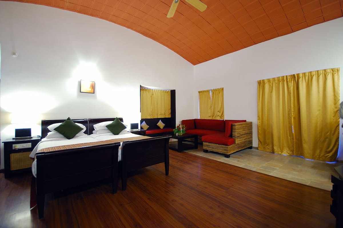 Habitación de hotel con dos camas, un sofá, una mesita y un ventilador de techo.