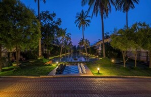 A well-lit outdoor area with a pool, palm trees, and a checkered pattern on the ground. - The Windflower Resorts and Spa (Mysore)