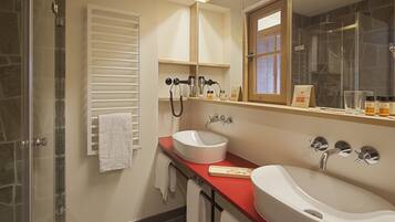 Un baño con cabina de ducha de vidrio, dos lavamanos y un espejo con marco de madera.