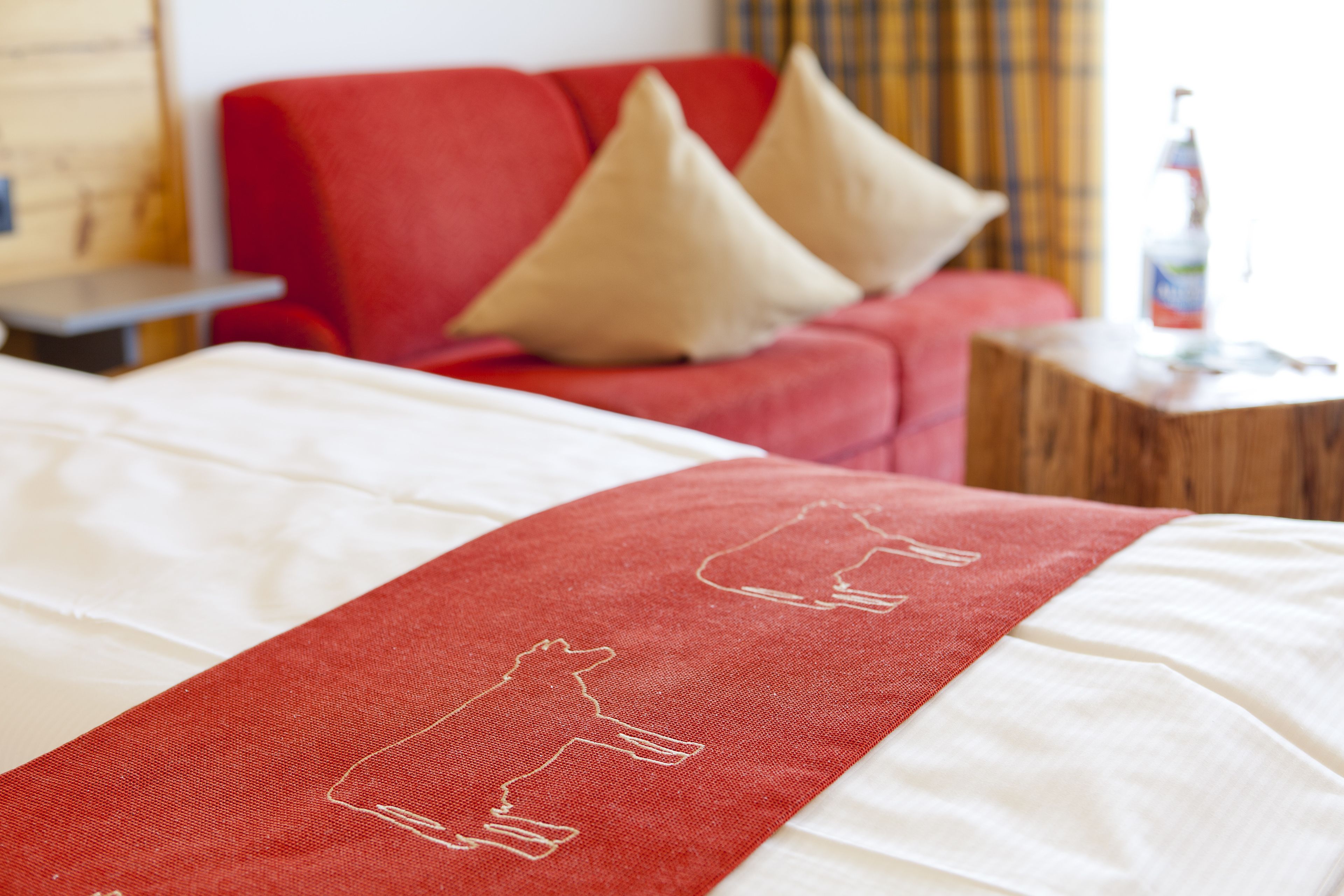 A bed with a red runner and a white pillow.