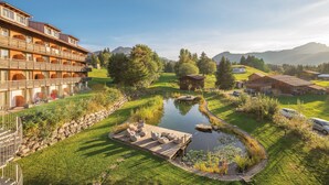 A hotel with a pool, wooden deck, and surrounding greenery. - Hotel Oberstdorf (Oberstdorf)
