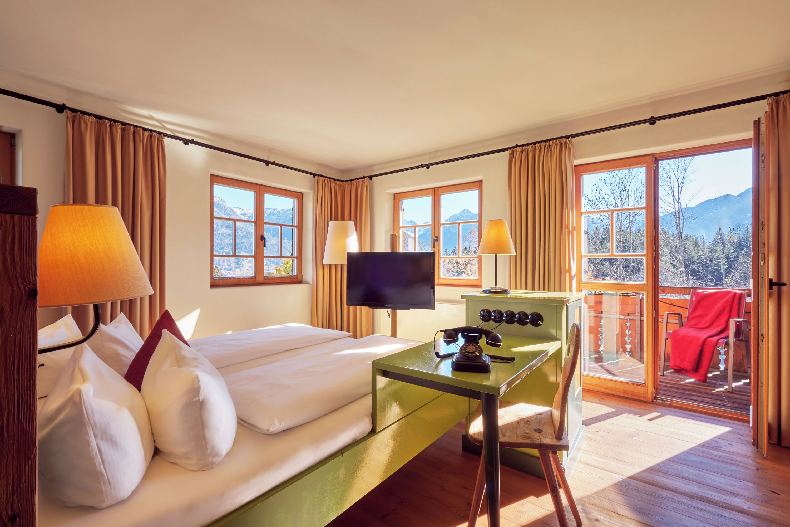 Ett hotellrum med en säng, ett skrivbord, en tv och en balkong med en stol.
