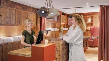 Ein Holzinterieur mit einer Rezeption, einem roten Sessel und einem Holzschrank mit Handtüchern.