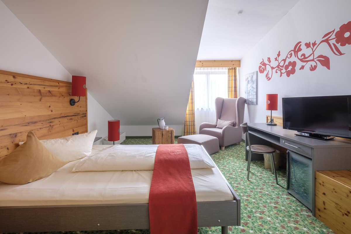 Une chambre d’hôtel avec un lit, un bureau avec une télévision, une chaise et une petite table.