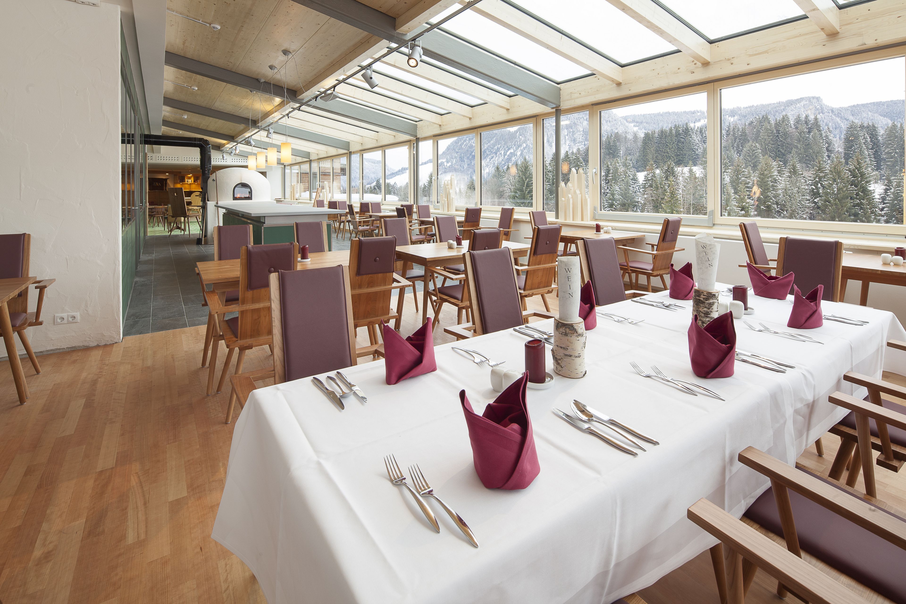 A spacious dining area with long tables set for a meal, large windows offering a view of snow-covered mountains, and a modern interior design.