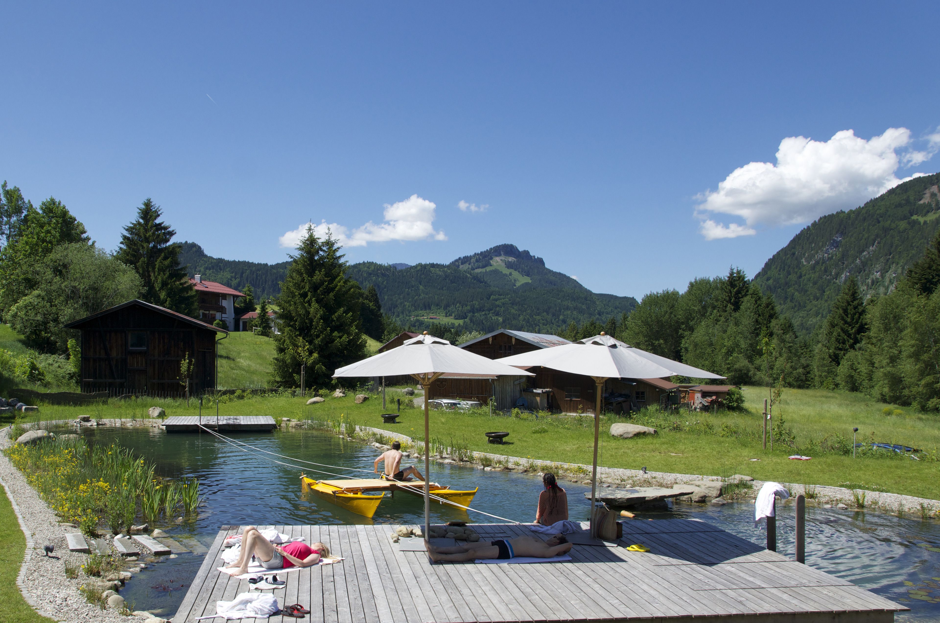A lakeside resort with wooden docks, boats, and umbrellas.