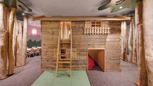 A wooden playhouse with a ladder, a small window, and a door.