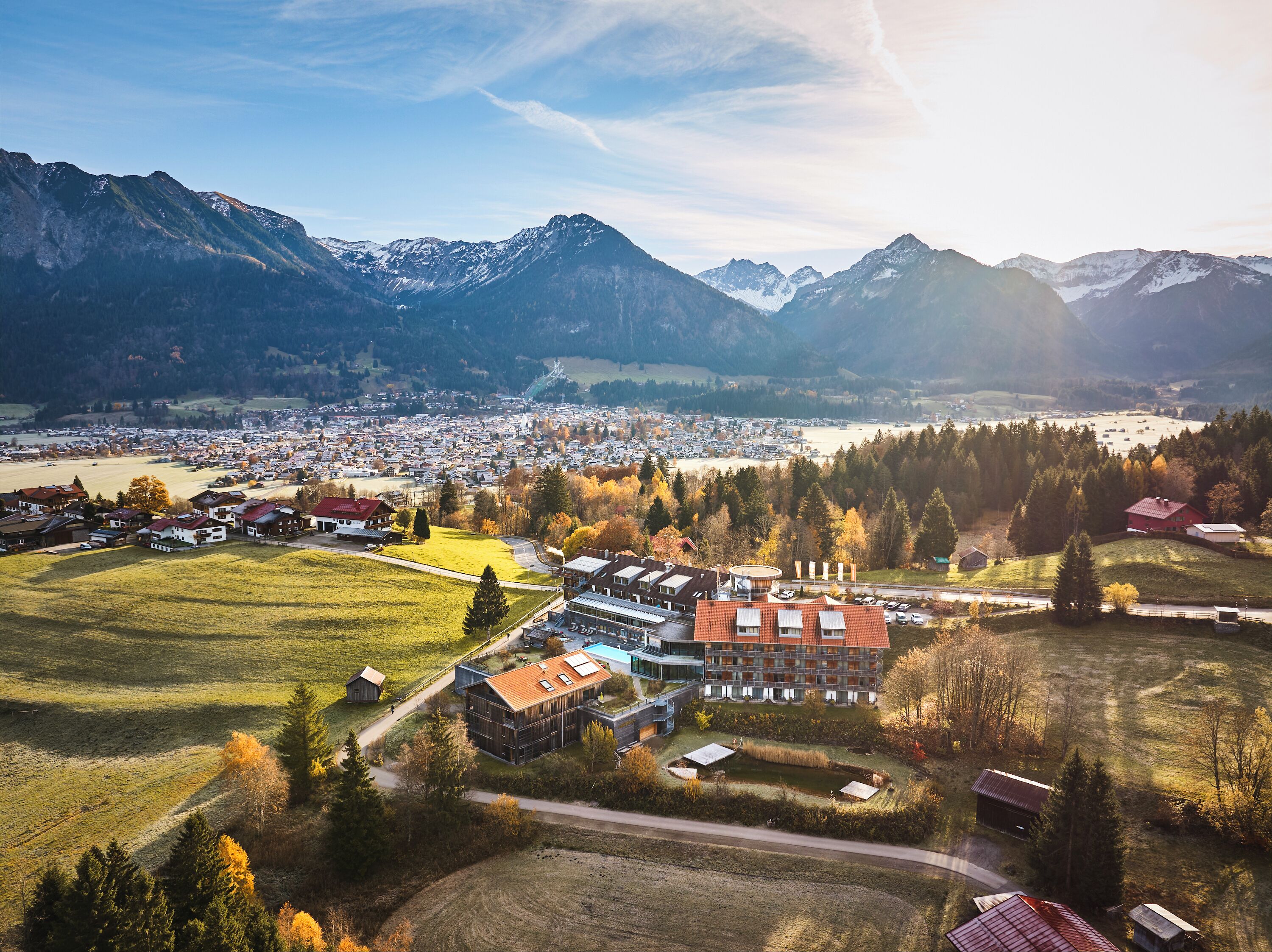 A town with a central building surrounded by fields and mountains in the background.