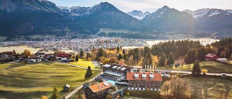 A town with a central building surrounded by fields and mountains in the background.