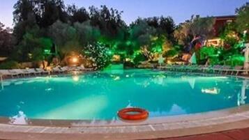 Une piscine équipée d’une bouée de sauvetage, entourée de chaises longues et de verdure.