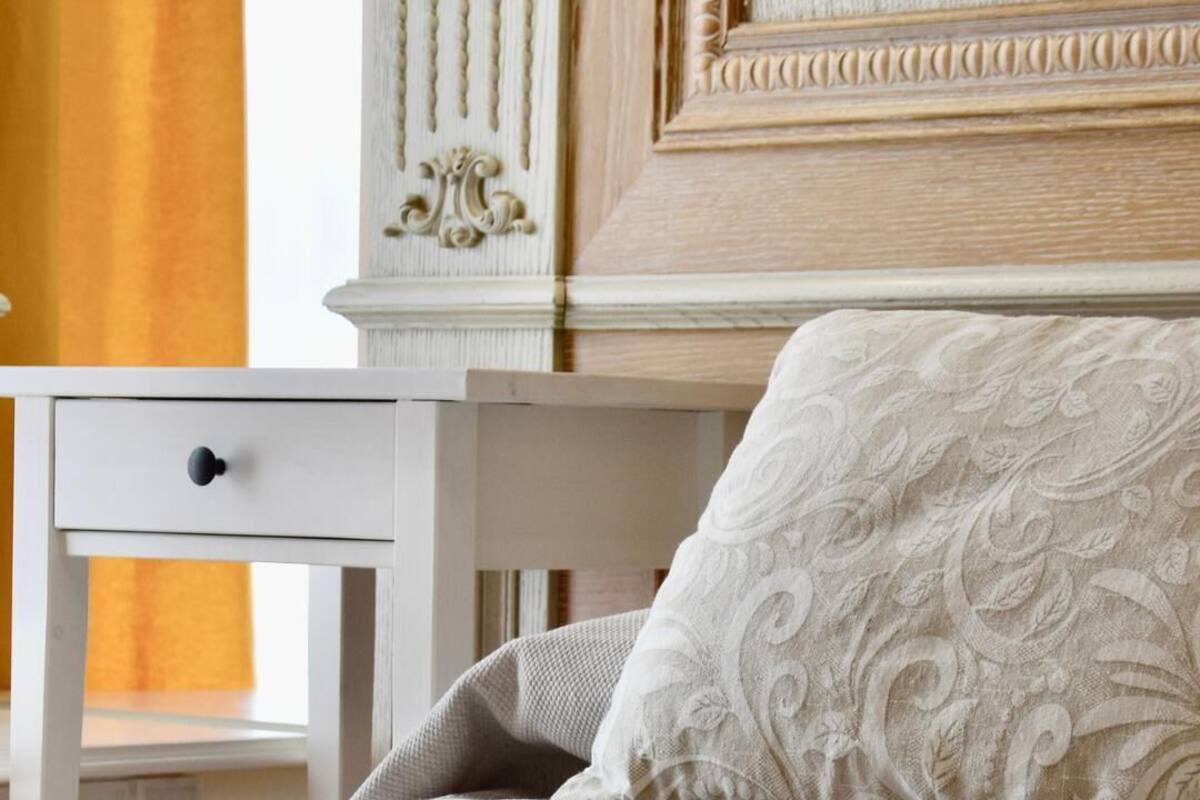 Un lit bien fait, avec un oreiller blanc et une table de chevet blanche dotée d’un tiroir.